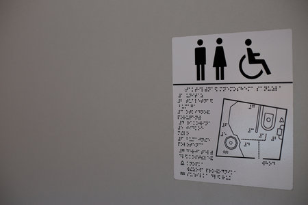 Public restroom sign featuring icons, along with tactile map for visually impaired. Sign emphasizes inclusivity, offering guidance through both visual and braille elements for universal accessの写真素材