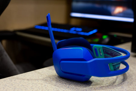 Close up shot of modern, illuminated blue gaming headset resting on table, with vibrant colors...
