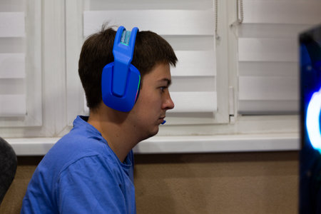 Computer gamer focused on a game. Side view of a guy wearing a gaming headset. Focused computer user...