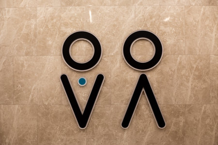 Wall with universal gender symbols for men and women indicating left for men and right for women in sex public restroom. Concept for hygiene and universal design for public accessible environmentの写真素材