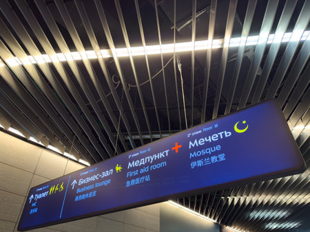 Ceiling sign in different languages at airport for navigation in large building. Directions to the restrooms, business lounge, first aid room and Muslim mosque. Caring for people at the airportの写真素材