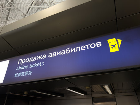 Airline ticket sales signage in three languages. Navigation and orientation at modern airport for passenger convenience. Purchasing airline tickets at the airport counterの写真素材