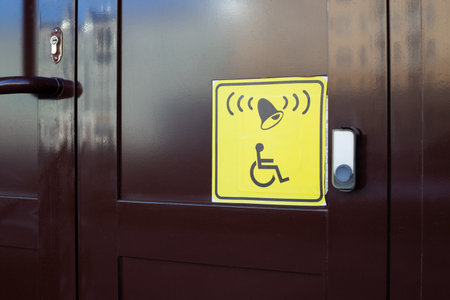 Standard wheelchair sign next to the call button at the building entrance. Accessible environment...