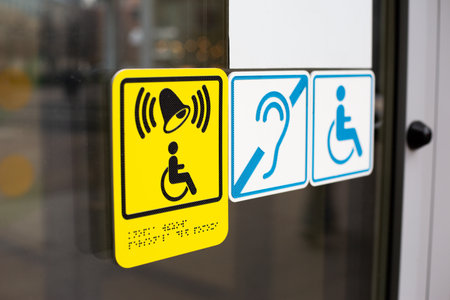 Disabled sign with bell and Braille text. Symbol of person in wheelchair next to accessibility signs...