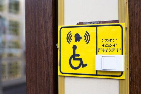 Sign with symbol of disabled person and text in Braille. Sign wheelchair symbol, bell icon and...