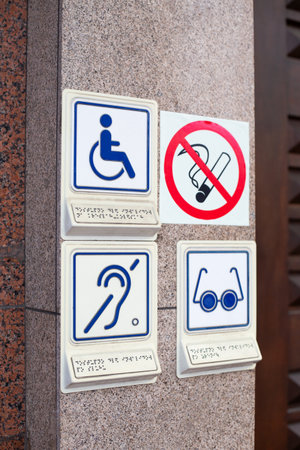 Set of disability icons, including wheelchair, deaf people and blind person. Hearing aid and problems with eyes. Signs at entrance to building for people with disabilities next to no smoking signの写真素材