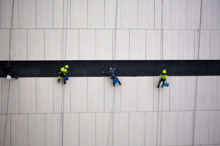 Large group of industrial climbers work at height and clean the building facade. Team specializing in working at height. Worker safety and insurance. Industrial climbing conceptの写真素材