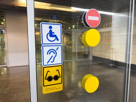 Plastic signs on glass wall near entrance with automatic sliding doors indicate accessible areas for...