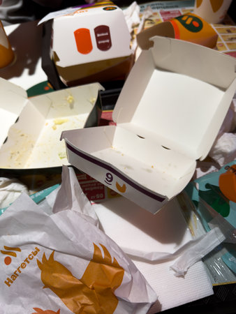 Moscow, Russia, November 21, 2025: Vertical photo of scattered burger, French fries and other food packaging at Vkusno fast food chain. Recyclable cardboard food packagingのeditorial素材