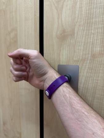 Vertical photo of gym locker being locked using club bracelet. Locking your belongings for...