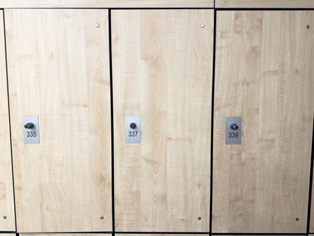 Locker doors with numbers. Public locker room in gym for storing items during workout. Locker doors with mechanism for secure storage, made of light wood. Interior of the locker roomの写真素材