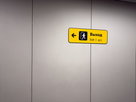 Modern interior with multilingual signage and building exit directions. Exit signs are located on wall. Assistance in escaping building during emergency and accidentの写真素材