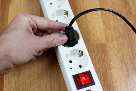 Person using extension cord. Appliance cord is plugged into extension cord on floor. Connecting...