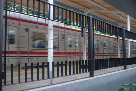 A fast-moving commuter train passes by a station platform in Jakarta, Indonesia.の写真素材