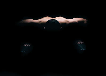 The light lighting the back of a man that is doing push-upsの写真素材