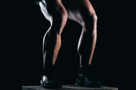 Studio photo of the lower part of a strong mans legs with black backgroundの写真素材