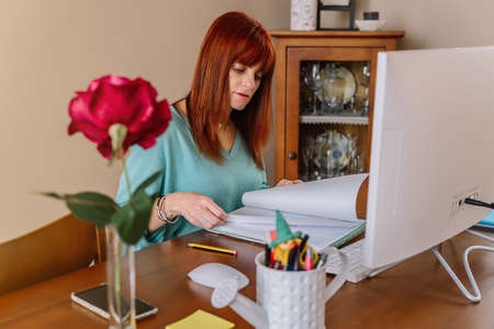 Woman consulting a notebook while teleworking