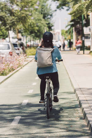 Woman riding a bicycle in the street with a backpackの写真素材