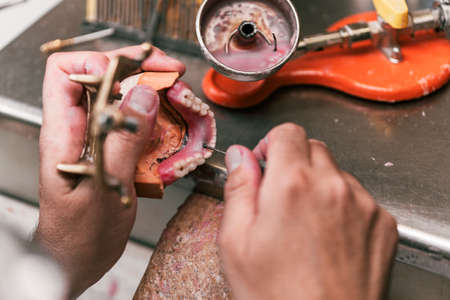 Hands of a dental technician fixing the paste on a dental prosthesisの写真素材