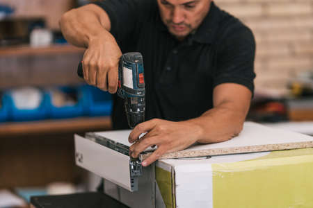 Drill being used by an man to make furniture in a workshopの写真素材
