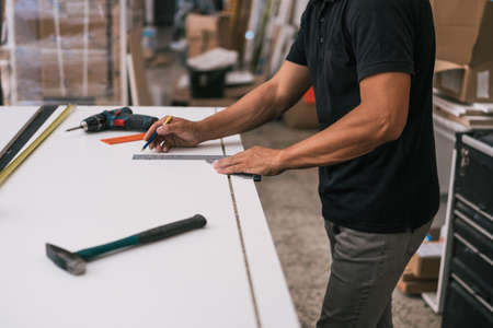 Man measuring a surface with a square in a workshopの写真素材