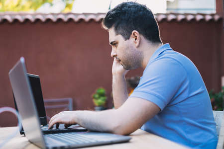 Profile of a young Caucasian man calling on a mobile phone while using a mobile phone holder to...