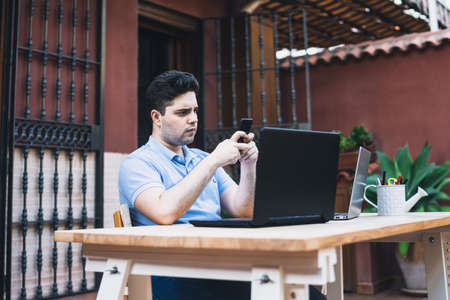 Man using a mobile phone while working with laptops trading cryptocurrencies outdoorsの写真素材
