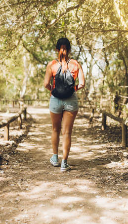 Woman walking along a rural path with shady treesの写真素材