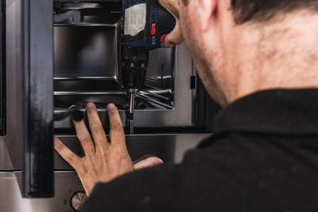 Worker placing a microwave to a kitchen cabinetの写真素材