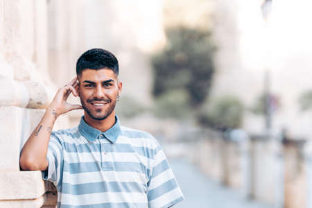 Portrait of a man leaning in a wall while smiling to camera outdoors