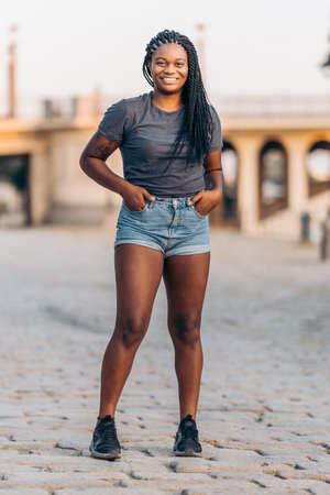 Young black woman standing outdoors with hands in the pocketsの写真素材
