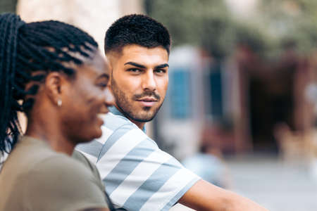 Young caucasian man facing the camera next to an afro woman outdoorsの写真素材