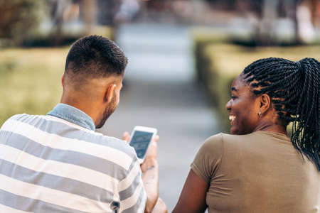 People of different ethnicities sitting on the street using a mobile phone