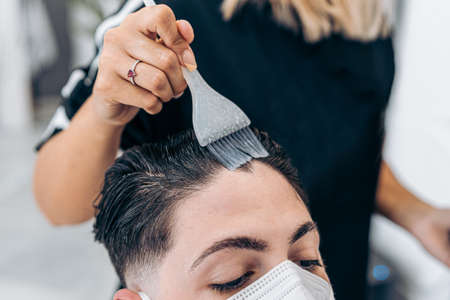 Hand of a hairdresser using a brush to coloring the hair of a man on a salonの写真素材