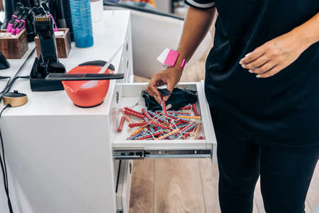 Hairdresser grabbing rollers from a drawer in a hairdressers shelfの写真素材