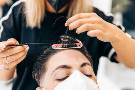 Hairdresser separating the hair of a client with a mask with an awl to curl themの写真素材