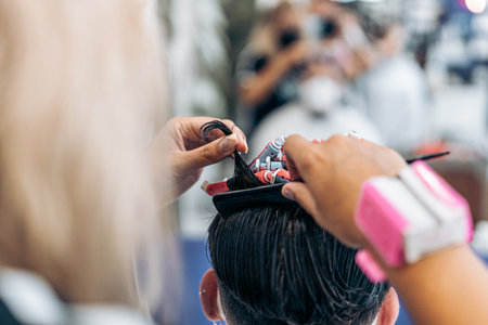 Photo with copy space of a hairdresser using a comb to curl the hair of a manの写真素材