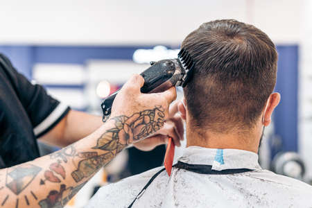 Barber cutting the hair of a man using an electric machineの写真素材