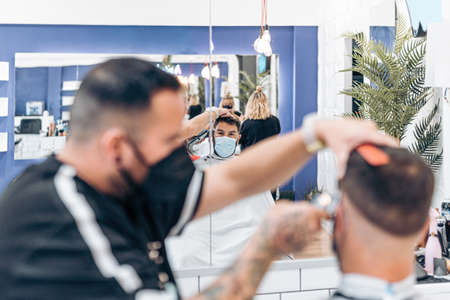 male costumer with mask reflected in a mirror of a barbershopの写真素材