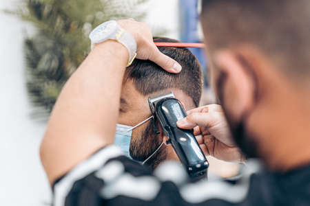 Close up view of a man with mask being shaved in a barber shop