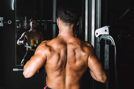 Strongman looking in the mirror while exercising in a gymの写真素材