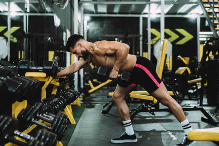 man doing exercises with a dumbbell in a gymnasiumの写真素材