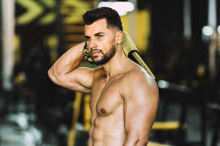 Portrait of a strong man drying himself with towel in a gymの写真素材
