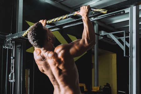 Strong male doing pull-ups on a bar in a gym
