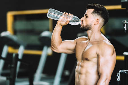 Photo with copy space of a strong caucasian man drinking water in a gymの写真素材