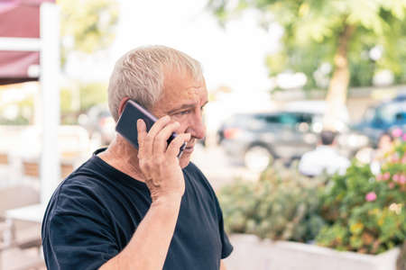 Old man talking with the mobile phone in the streetの写真素材