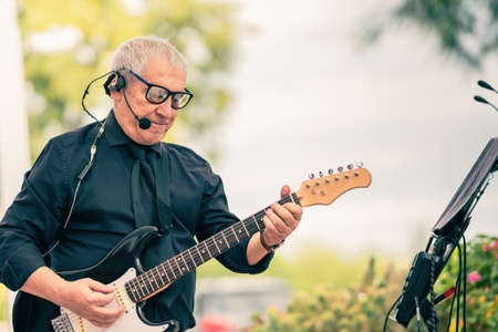 Photo with copy space of an old musician playoing the electric guitar outdoorsの写真素材