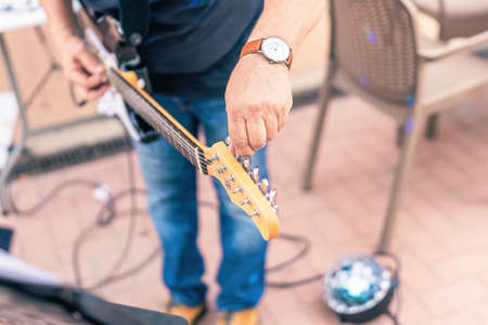 Close up view of a musician tuning his electric guitar on stageの写真素材