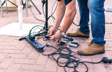 Sound technician picking up cables from the floor after a live concertの写真素材