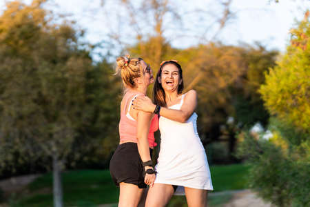 Two friends laughing while standing in a parkの写真素材